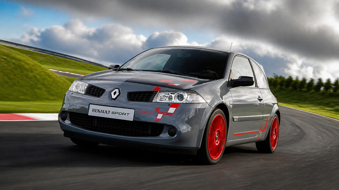 Carro esportivo Renault cinza com rodas vermelhas em pista de corrida sob céu nublado.