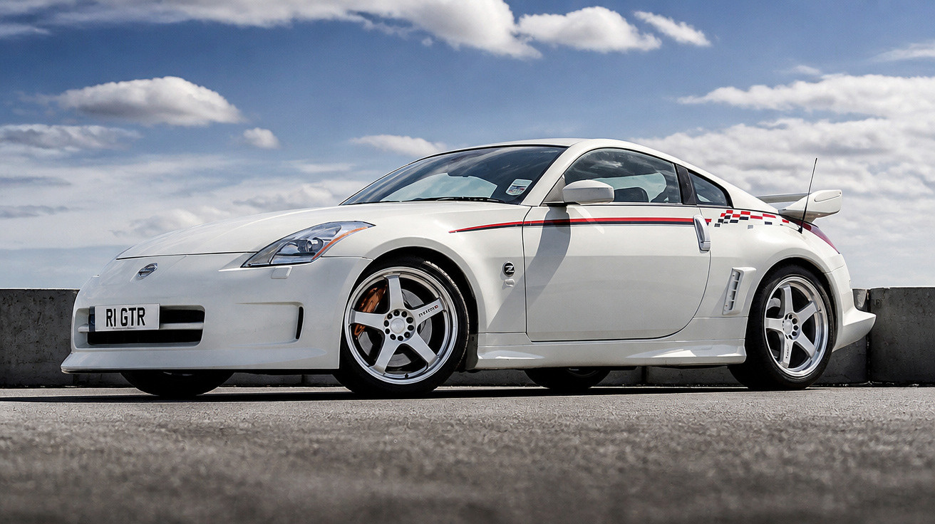 Carro esportivo branco Nissan 350Z estacionado em área externa sob céu parcialmente nublado.