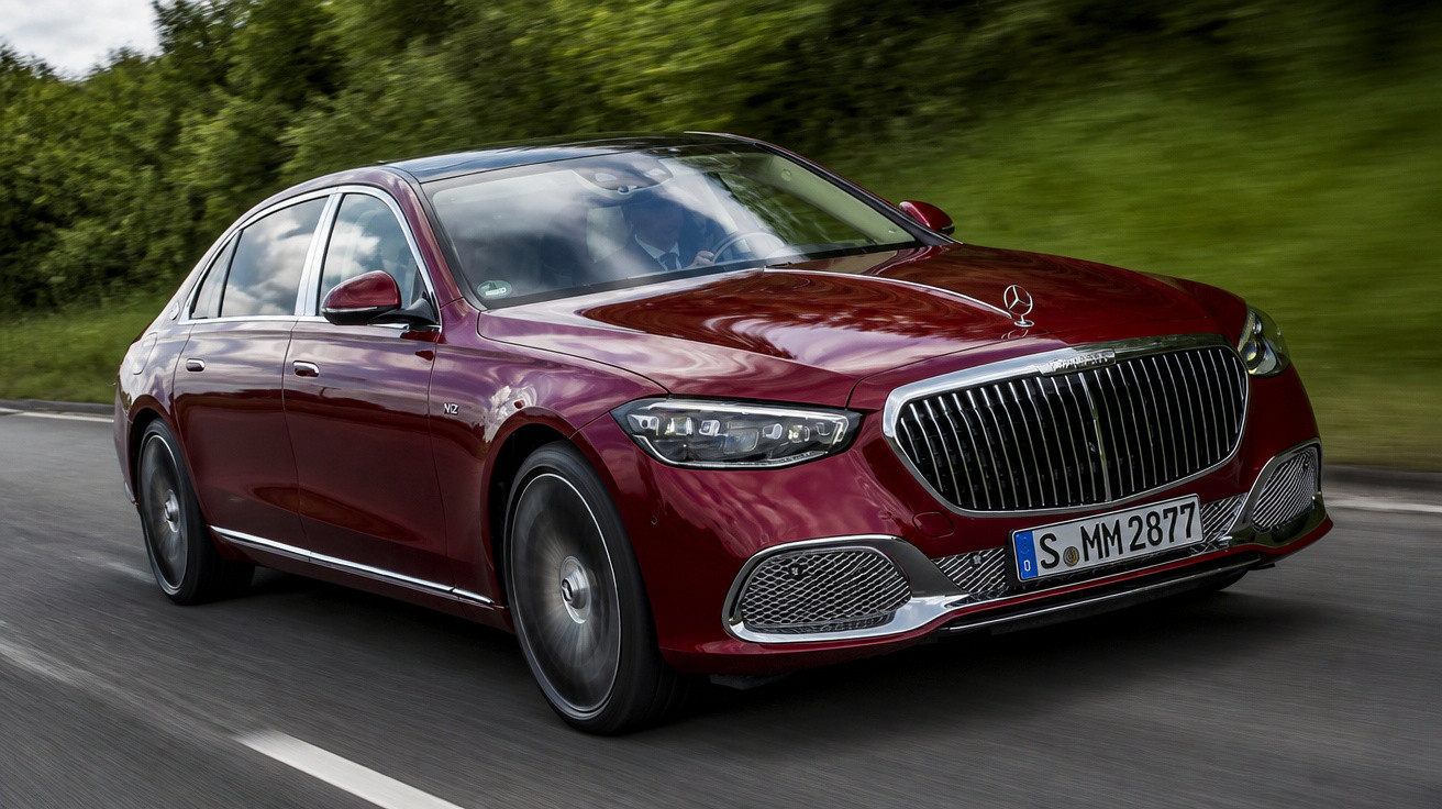 Carro Mercedes-Benz vermelho dirigido em estrada cercada por vegetação verde.