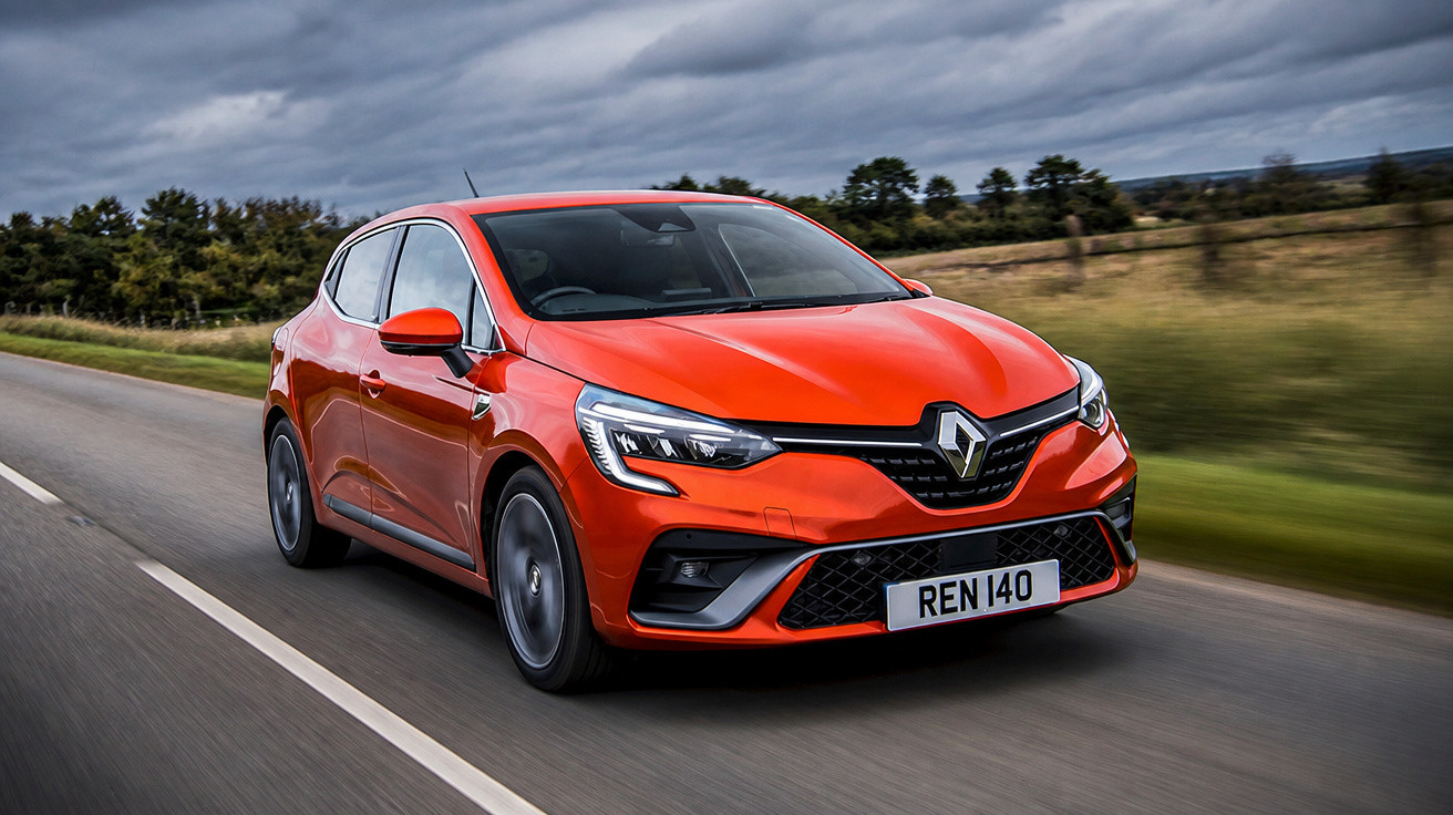 Carro Renault vermelho dirigindo em estrada com céu nublado e vegetação ao fundo.