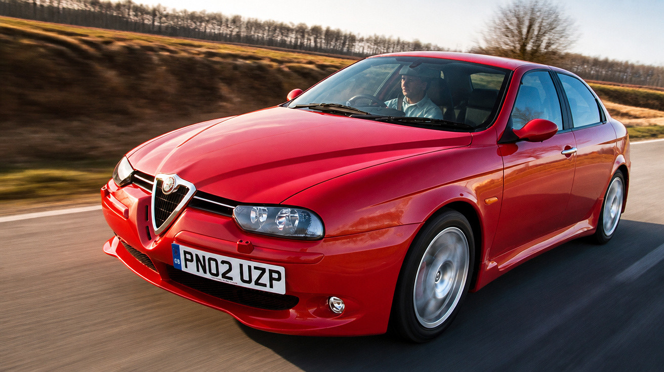 Carro vermelho Alfa Romeo em movimento em estrada rural com motorista ao volante.