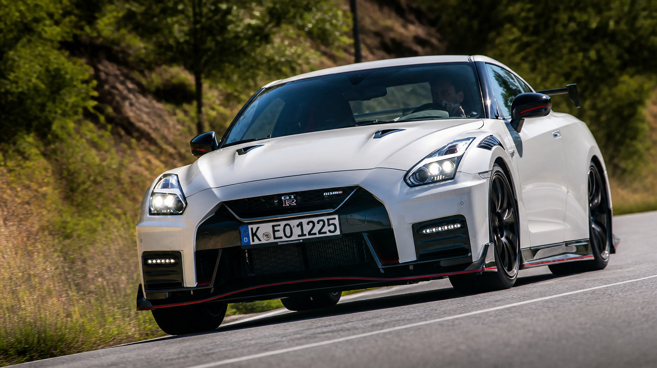 Carro esportivo branco Nissan GT-R Nismo acelerando em estrada cercada por vegetação.