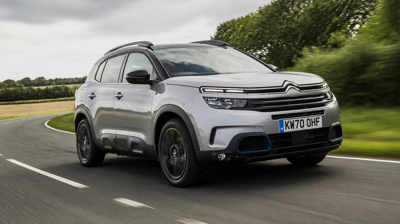 Carro SUV cinza prata Citroën em movimento em estrada curvada com vegetação ao fundo em dia nublado.