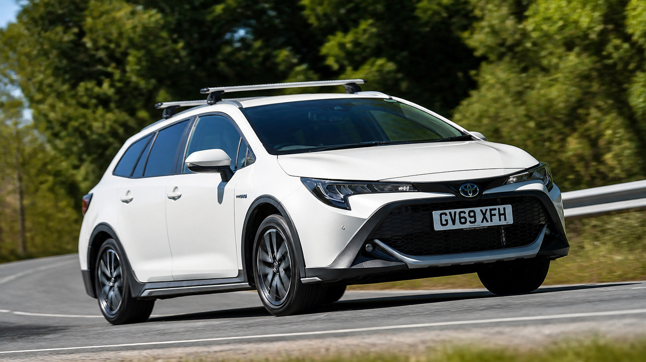 Carro branco Toyota híbrido em curva de estrada cercada por árvores verdes.