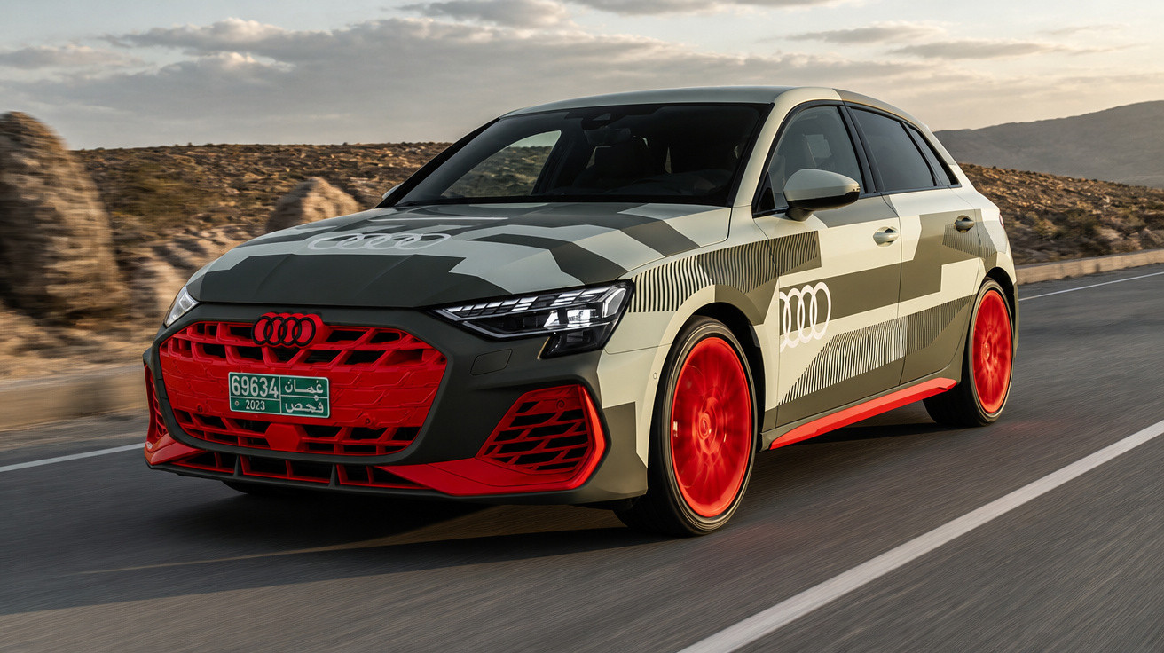 Carro Audi hatch cinza com detalhes vermelhos dirigindo em estrada deserta ao entardecer.