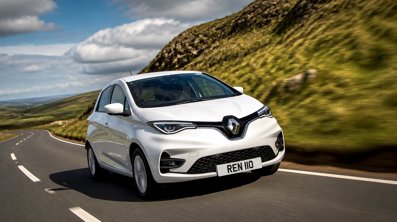 Carro branco Renault elétrico em estrada sinuosa com colinas verdes ao fundo em dia nublado.