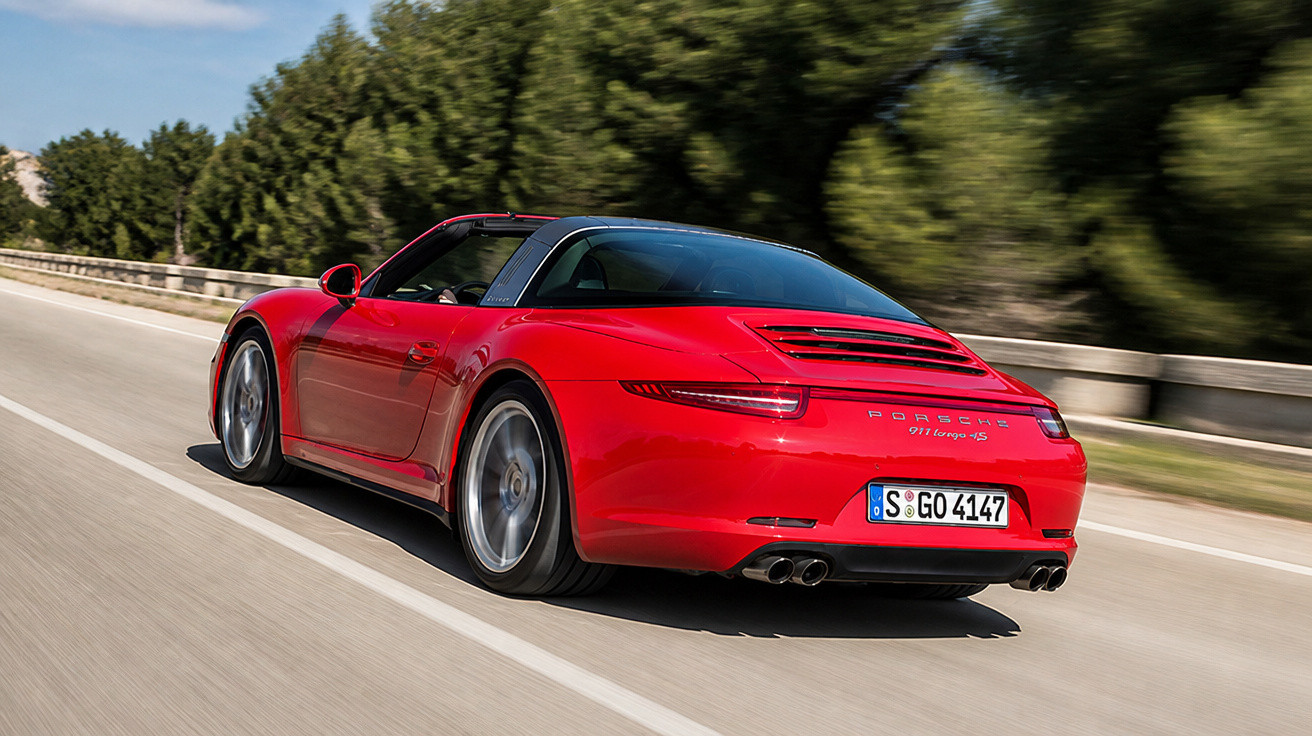 Carro esportivo Porsche 911 Targa 4S vermelho em alta velocidade em estrada asfaltada com árvores ao fundo.