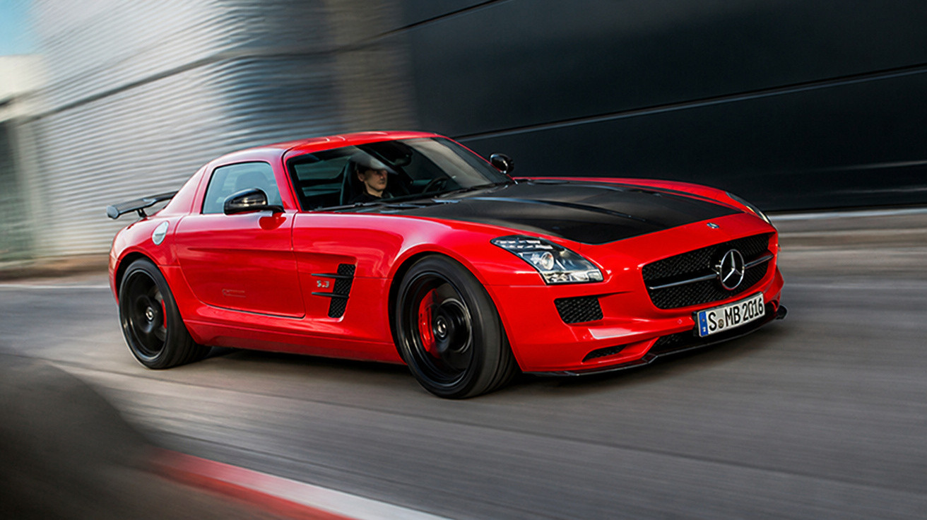 Carro esportivo Mercedes-Benz vermelho com capô preto em movimento em pista urbana.