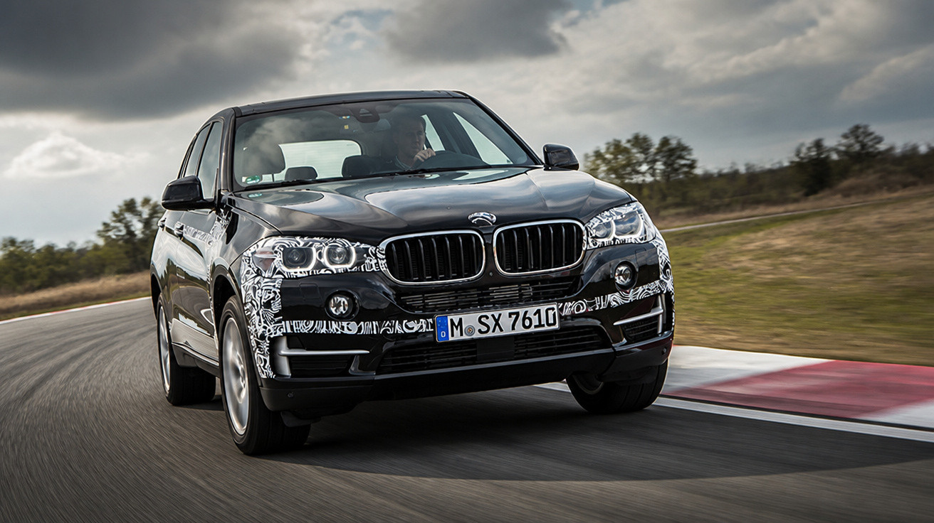 Carro preto BMW dirigindo em pista curva com céu nublado ao fundo.
