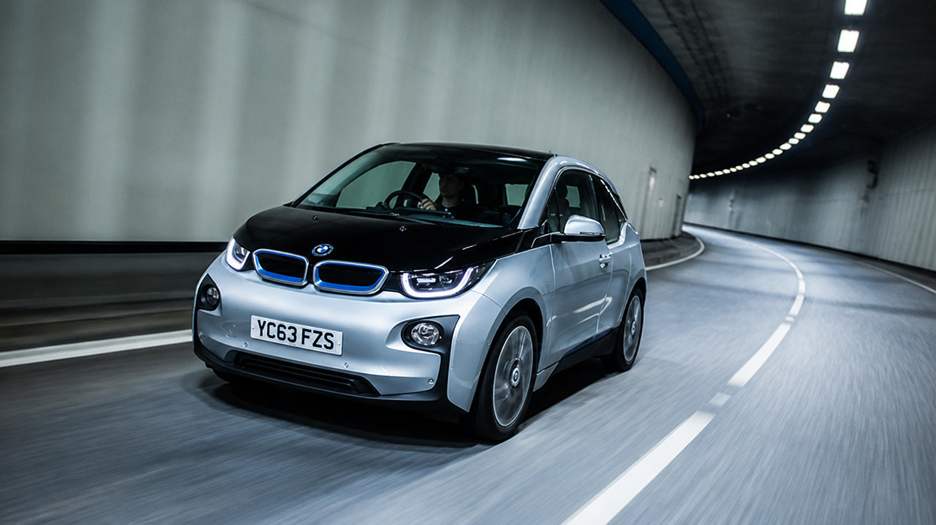 Carro elétrico BMW cinza e preto transitando dentro de túnel iluminado.