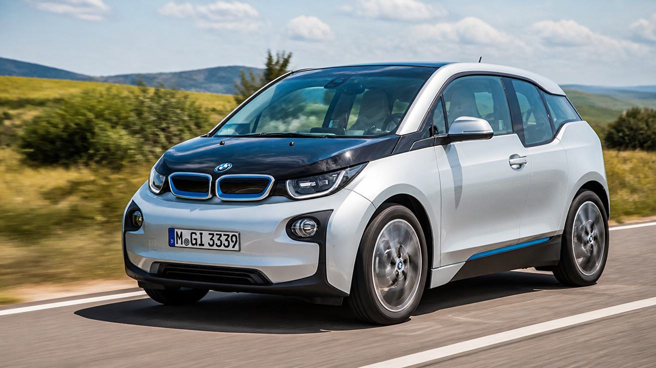 Carro elétrico BMW i3 branco com capô preto em estrada cercada por vegetação e colinas ao fundo.