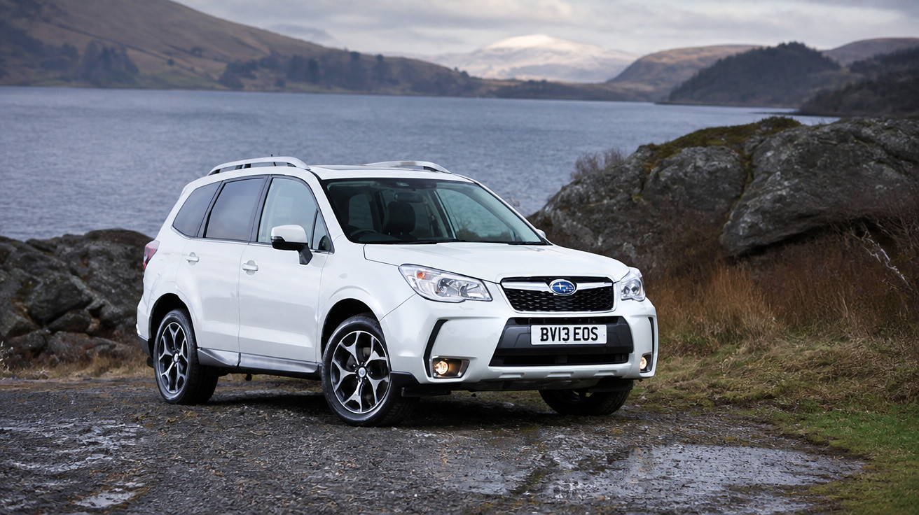 Carro SUV branco estacionado em área rochosa próxima a um lago com montanhas ao fundo.