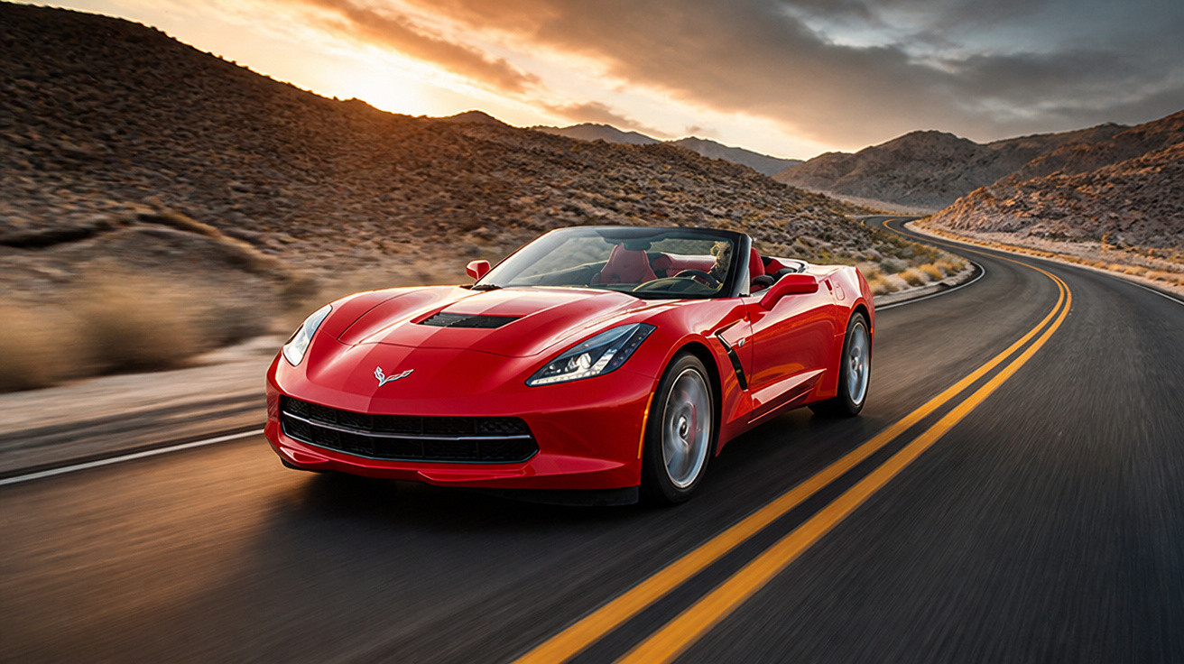 Carro esportivo conversível vermelho acelerando em estrada sinuosa no deserto ao entardecer.