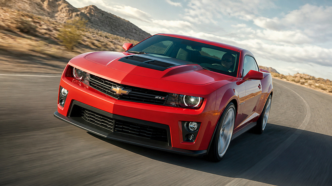 Carro esportivo vermelho Chevrolet ZL1 em estrada curva com paisagem desértica ao fundo.