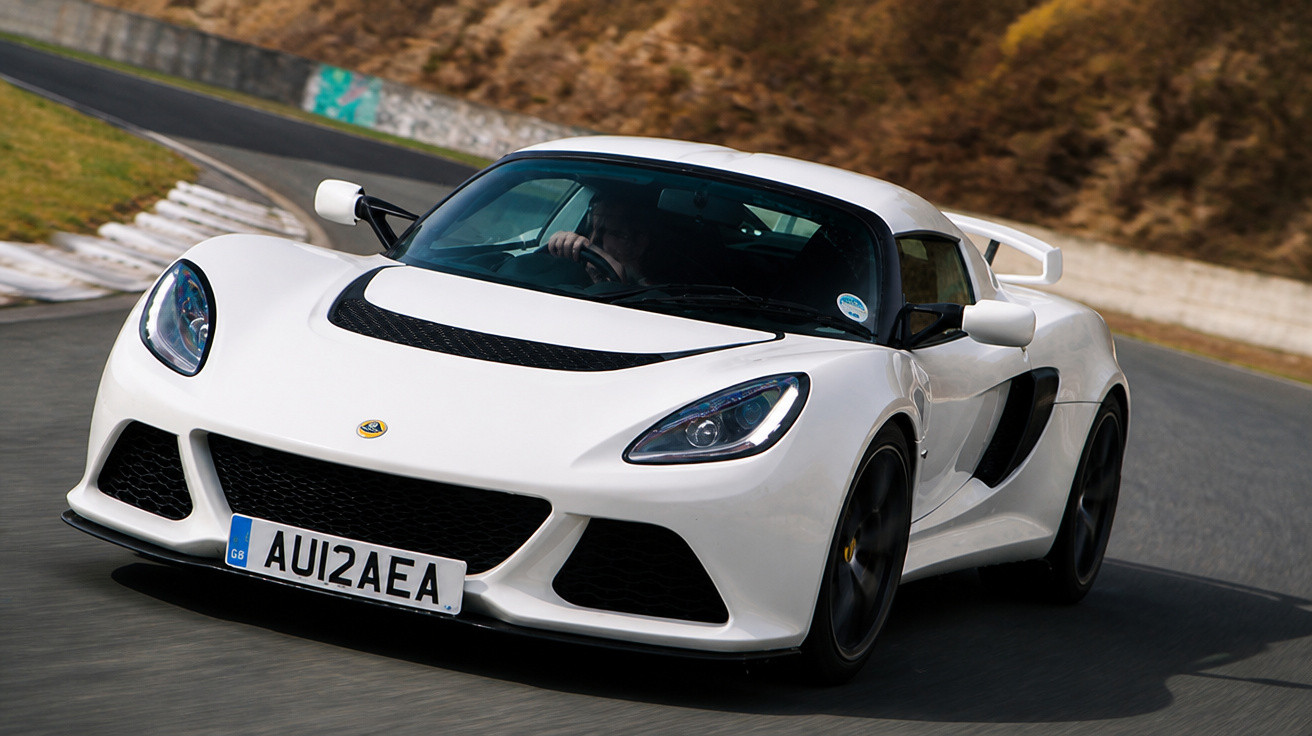 Carro esportivo branco na pista de corrida em curva, com detalhes aerodinâmicos e rodas pretas.