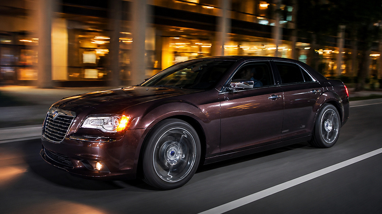 Carro sedan preto em movimento rápido à noite em avenida urbana iluminada.