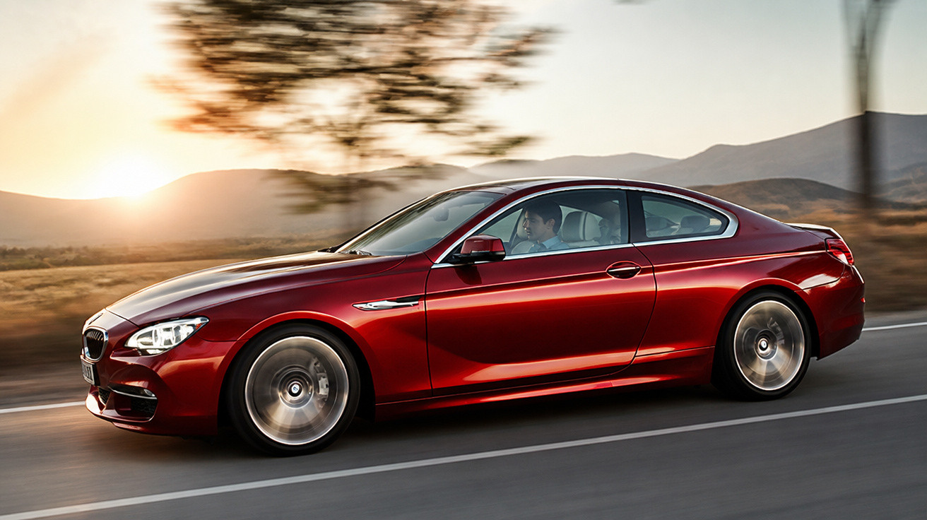 Carro esportivo vermelho em movimento na estrada ao pôr do sol com motorista masculino.