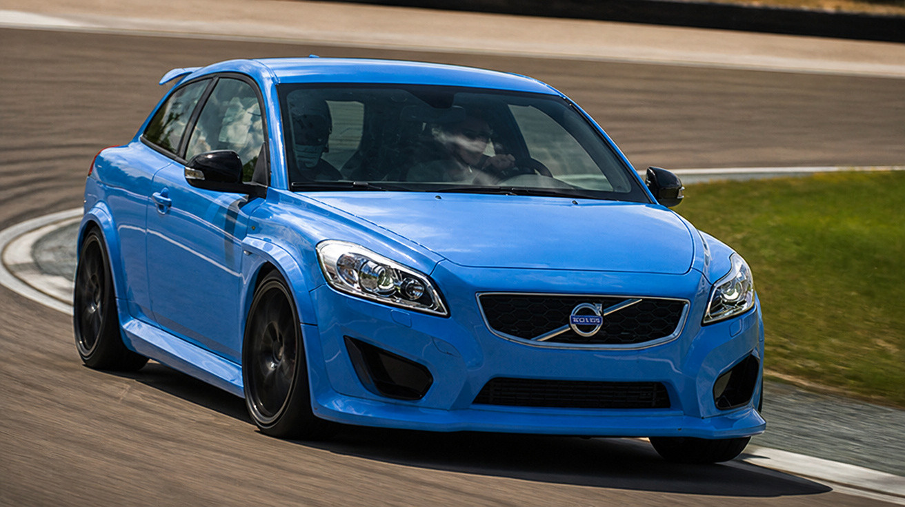 Carro azul Volvo acelerando em curva de pista com detalhes aerodinâmicos e rodas pretas.