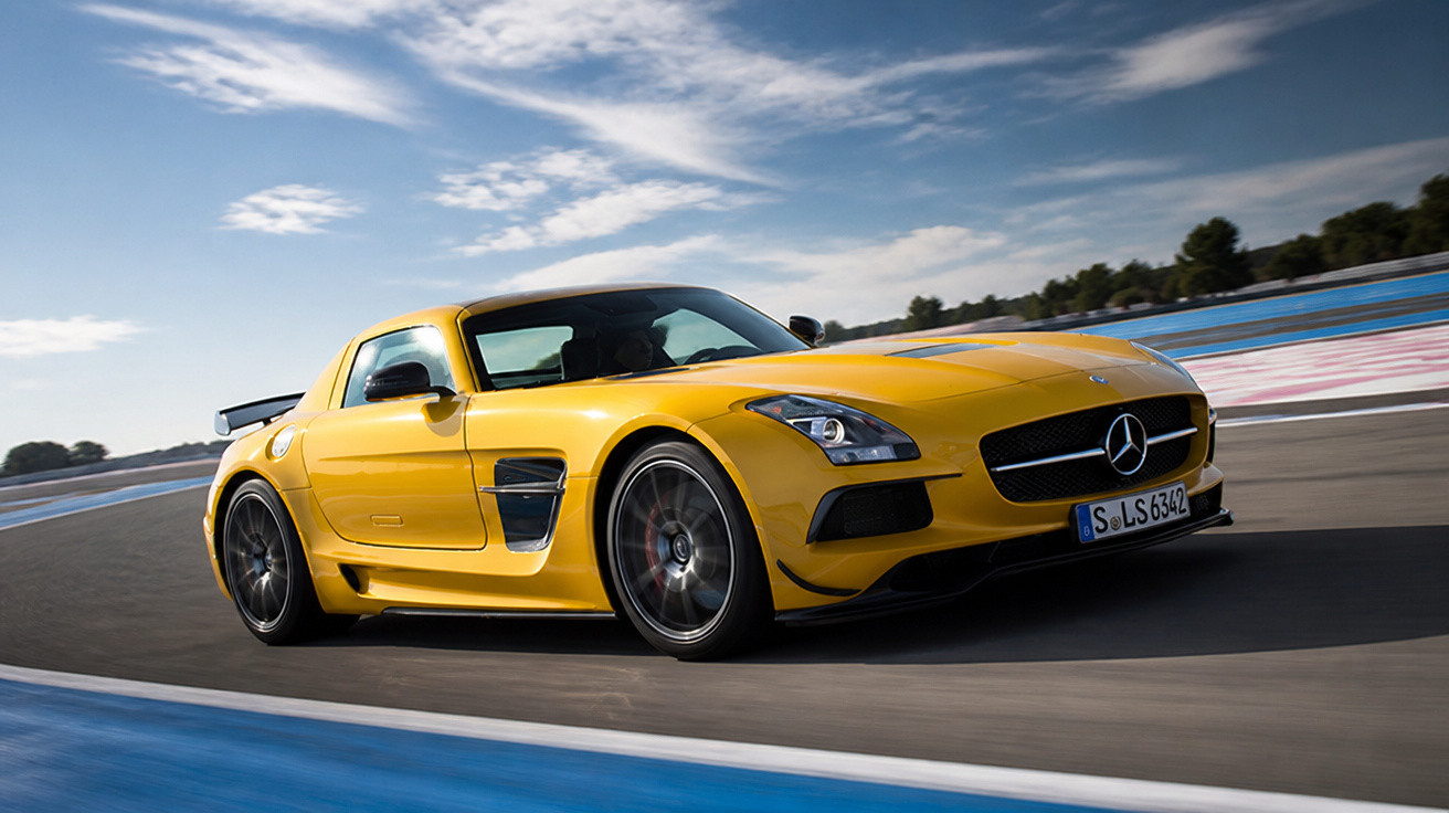 Carro esportivo amarelo Mercedes-Benz em alta velocidade em pista de corrida com céu parcialmente nublado.