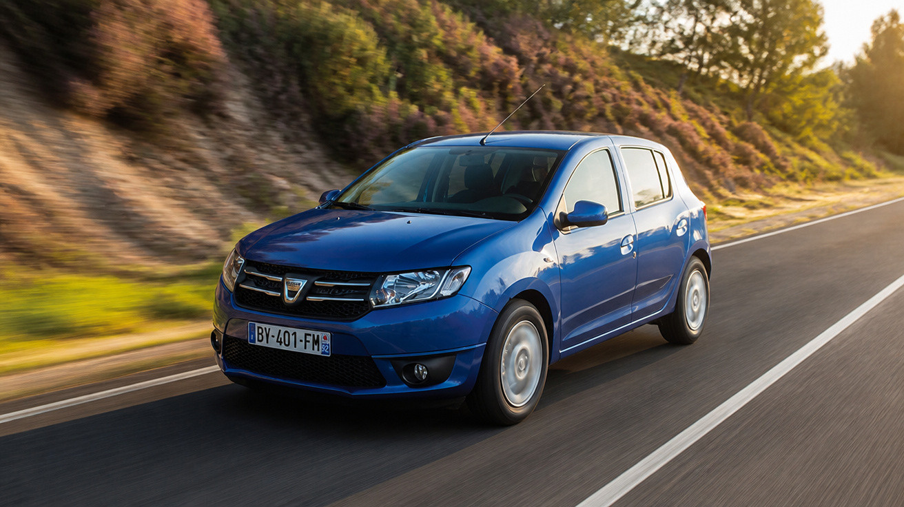 Carro azul compacto em movimento em estrada asfaltada com vegetação ao lado durante o dia.