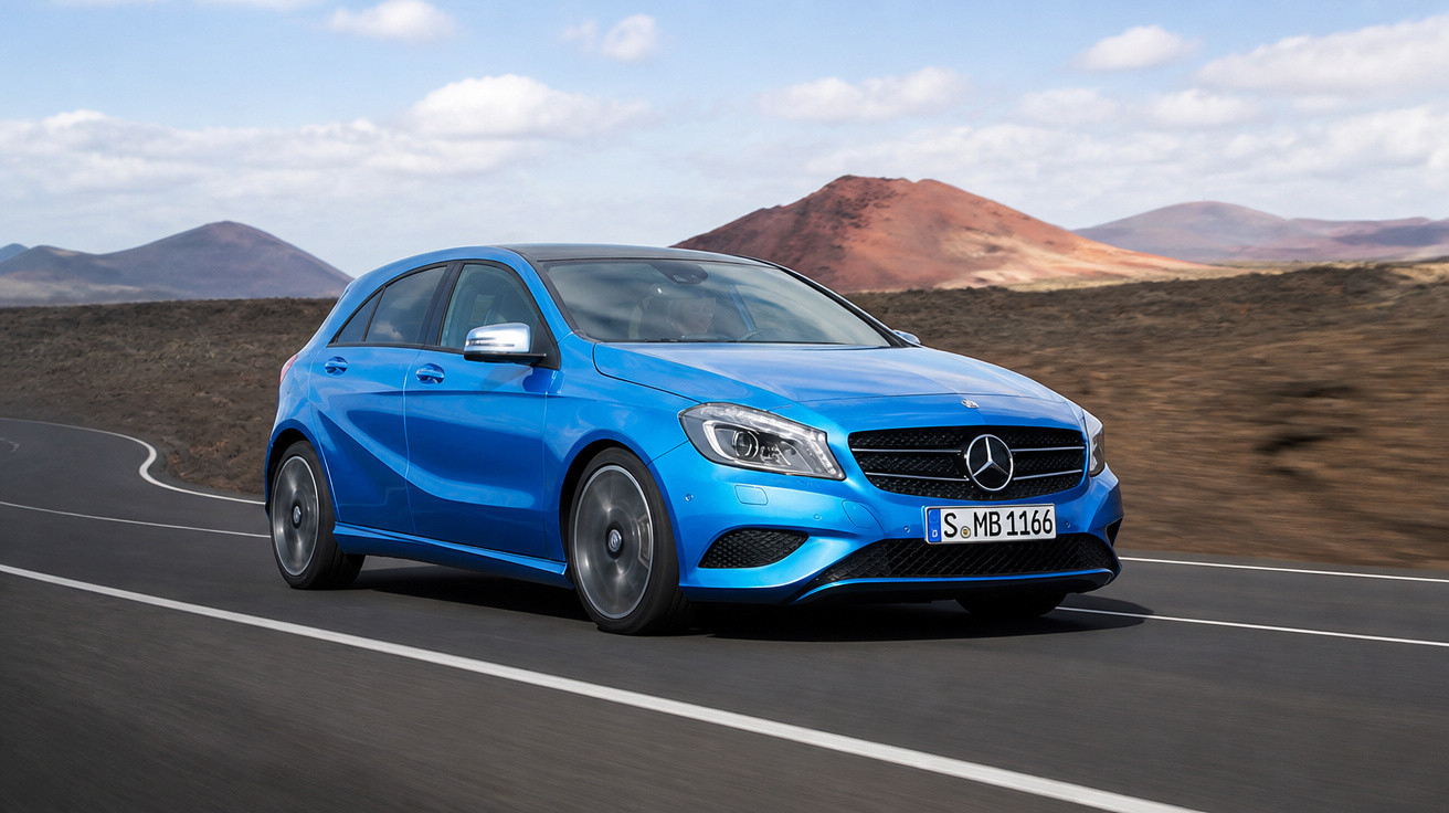 Carro Mercedes-Benz azul em estrada curva com paisagem árida e colinas ao fundo sob céu nublado.