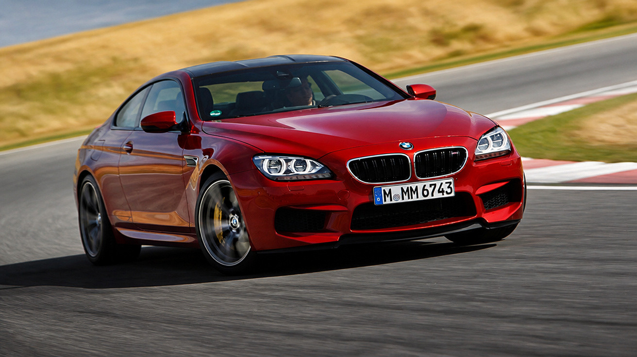 Carro esportivo vermelho BMW em alta velocidade fazendo curva em pista de corrida asfaltada.