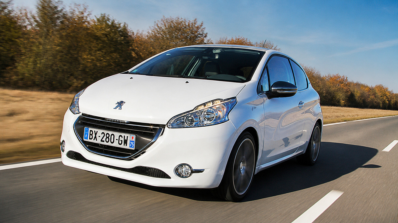 Carro branco da marca Peugeot trafegando em estrada reta com árvores ao fundo em dia ensolarado.