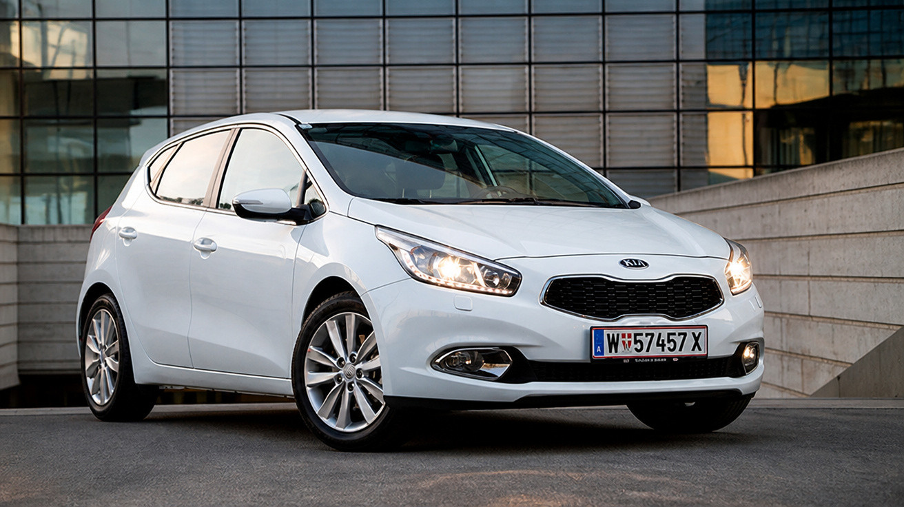 Carro branco Kia Hatch estacionado em área urbana moderna com faróis acesos.