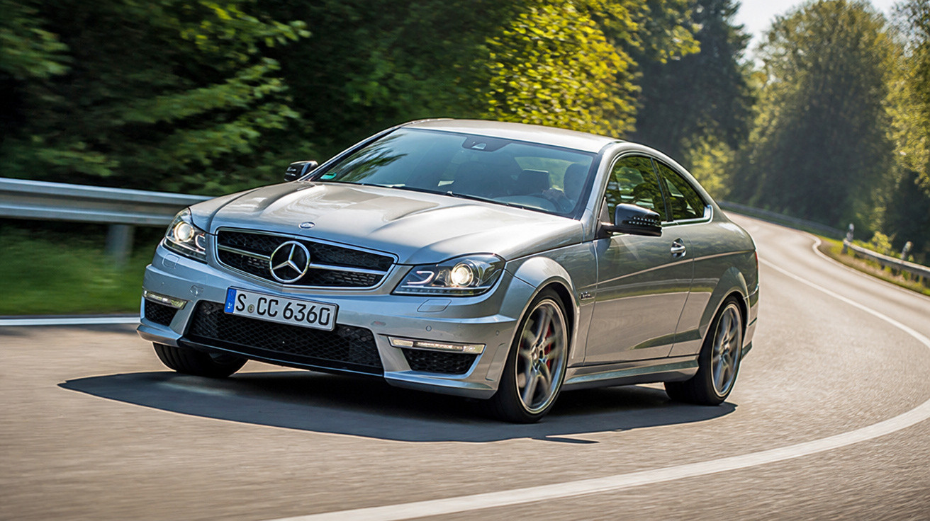 Carro esportivo Mercedes-Benz prata dirigindo em estrada curva cercada por árvores verdes.