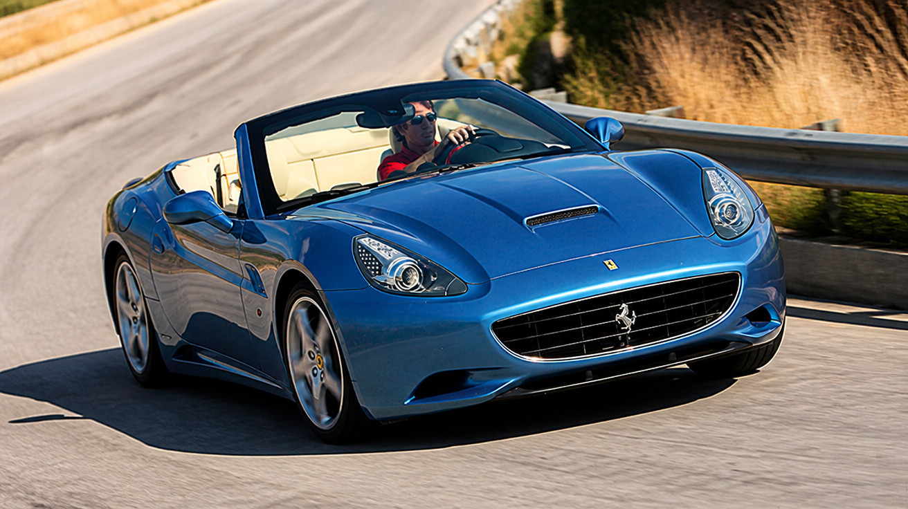 Carro esportivo conversível azul com motorista dirigindo em estrada curva ensolarada.
