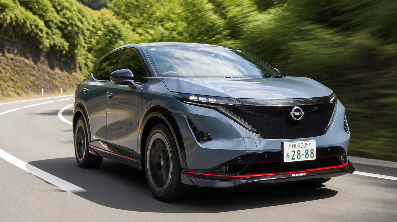 Carro elétrico Nissan SUV em movimento em estrada sinuosa cercada por vegetação verde.