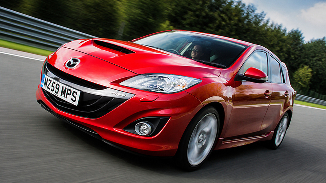 Carro esportivo hatchback vermelho Mazda em alta velocidade na pista de corrida.