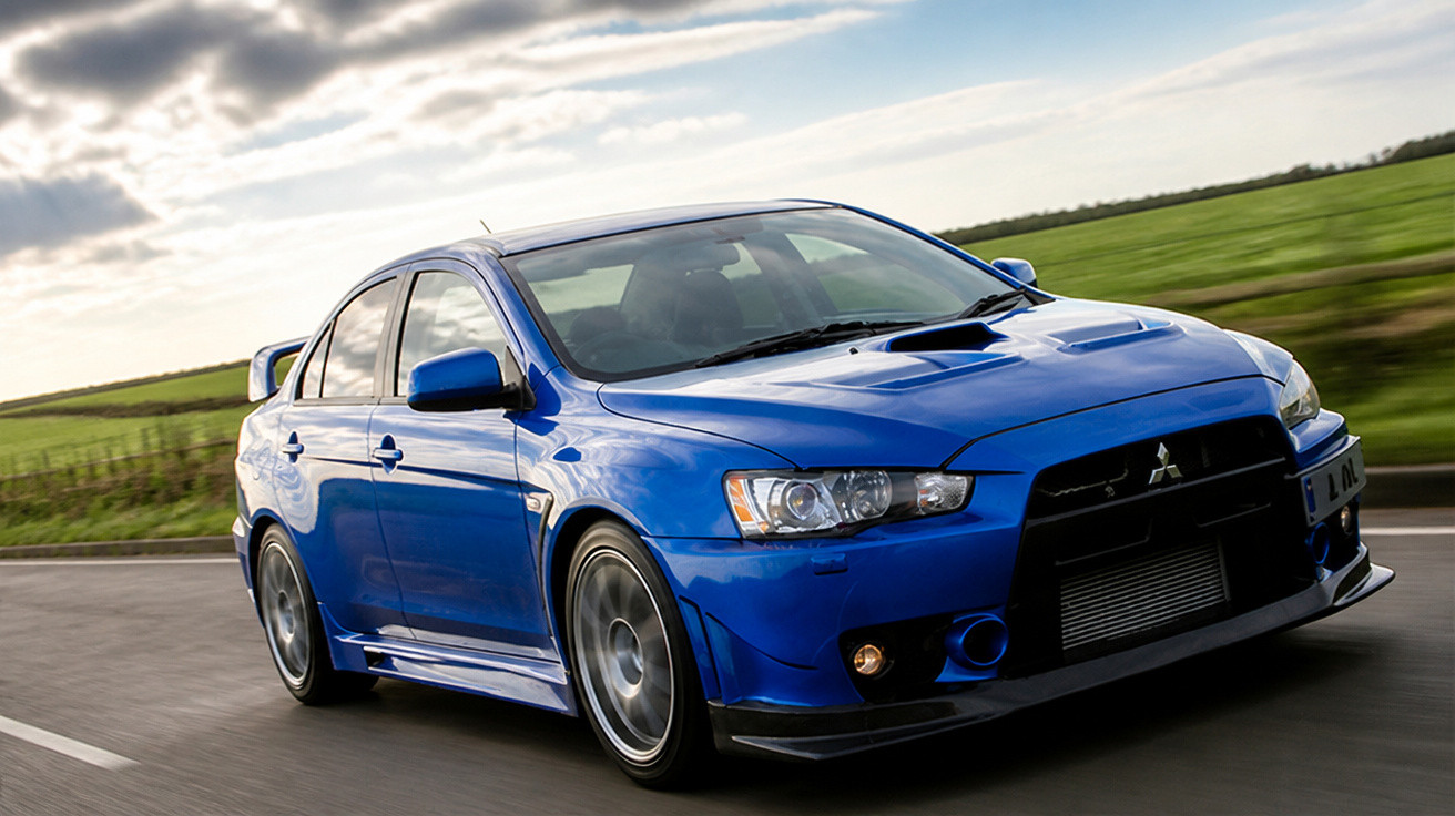Carro esportivo azul Mitsubishi Lancer Evo em movimento na estrada com campo verde ao fundo.