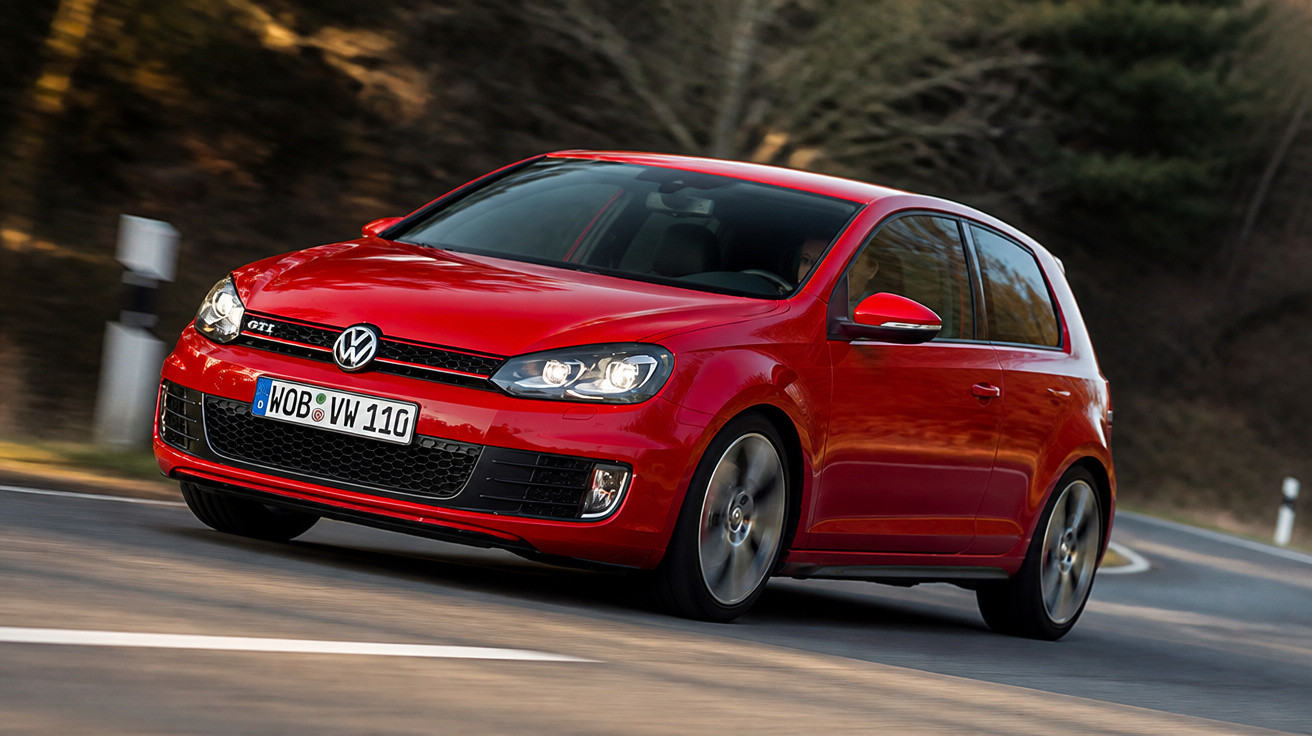 Carro Volkswagen Golf GTI vermelho em alta velocidade em curva de estrada asfaltada.