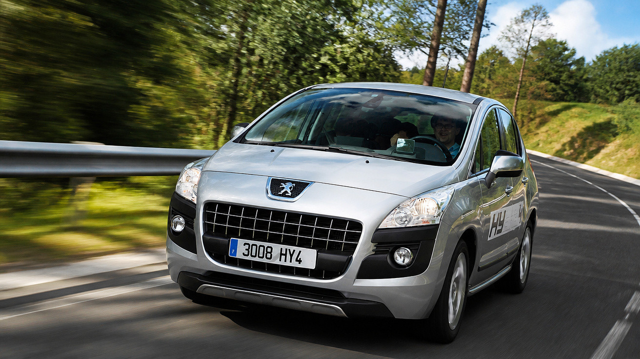 Carro prata Peugeot 3008 em movimento em estrada sinuosa cercada por árvores e natureza.