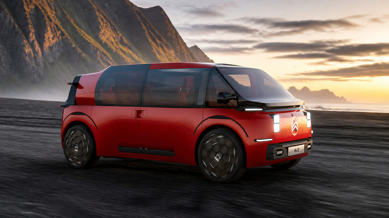 Carro elétrico compacto vermelho da Citroën em estrada preta com montanhas ao fundo ao pôr do sol.