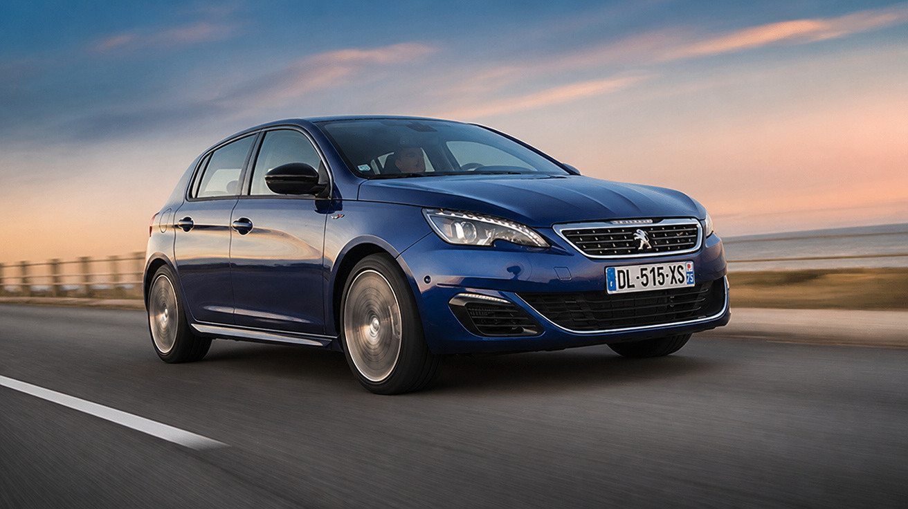 Carro Peugeot azul em movimento na estrada durante o pôr do sol à beira-mar.