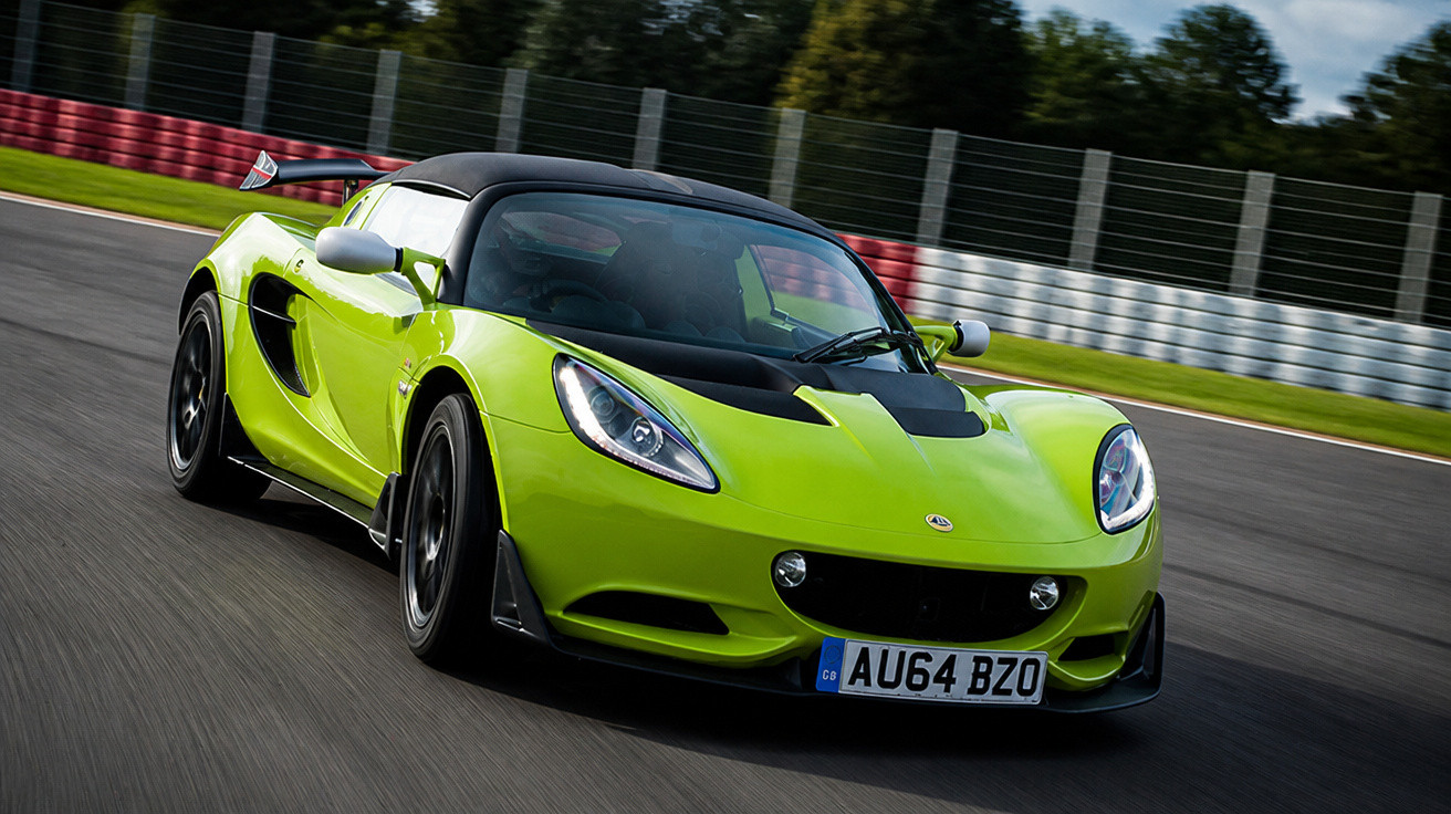 Carro esportivo verde limão em alta velocidade em pista de corrida, com placas britânicas.