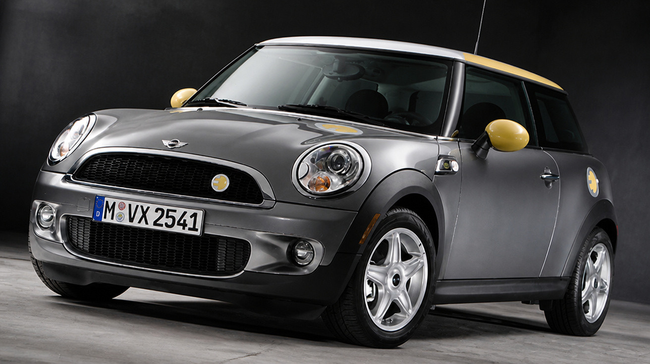 Carro Mini Cooper cinza com detalhes amarelos, visto de frente em estúdio escuro.