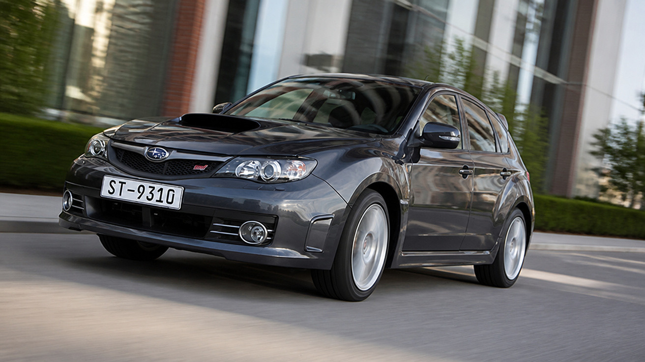 Carro esportivo Subaru preto em movimento em uma rua urbana durante o dia.