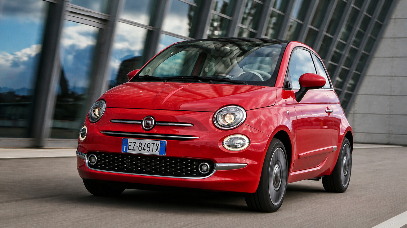 Carro vermelho Fiat 500 em movimento com prédio moderno ao fundo em dia claro.