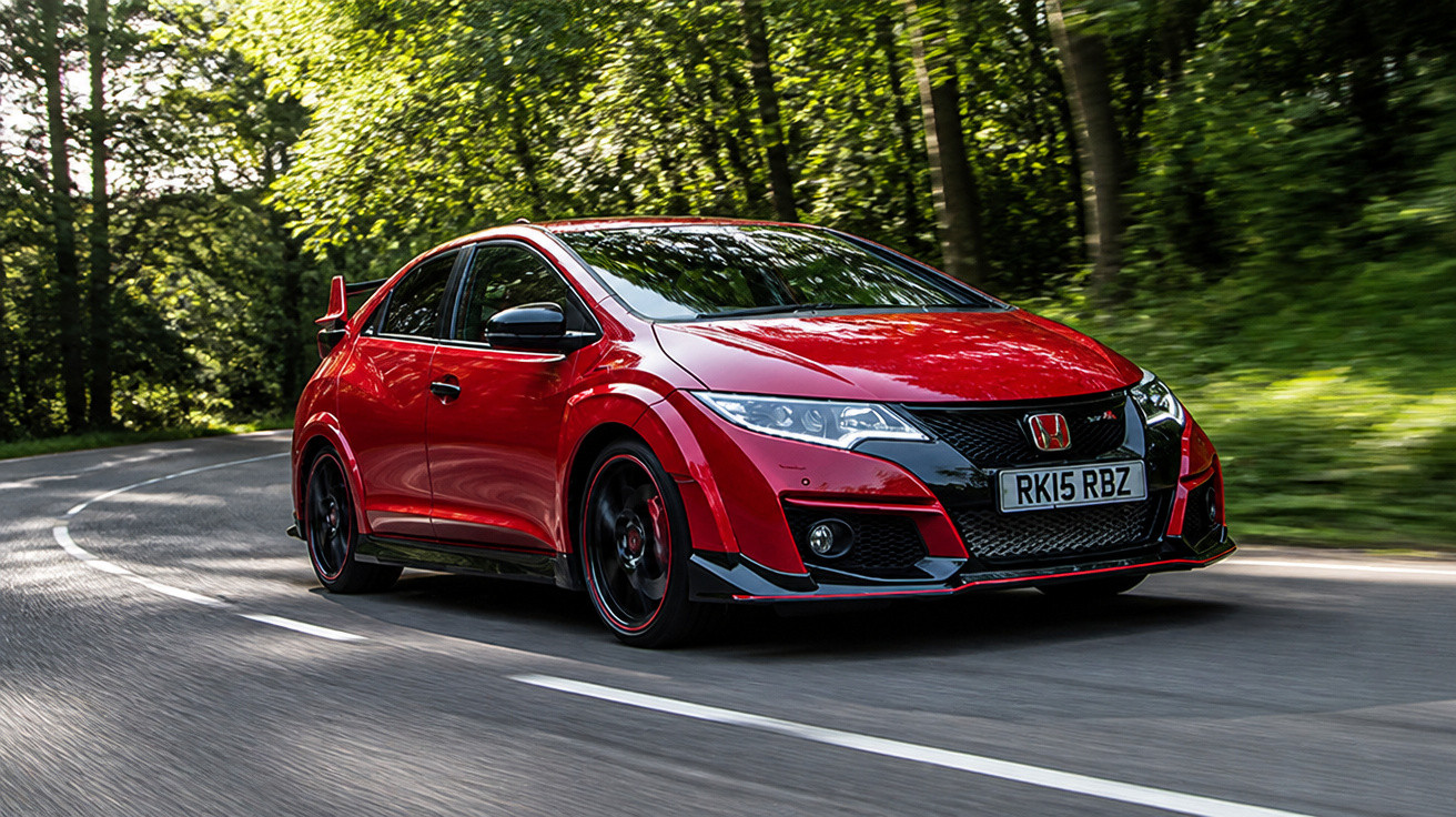 Carro esportivo vermelho Honda em estrada sinuosa cercada por árvores verdes em movimento.