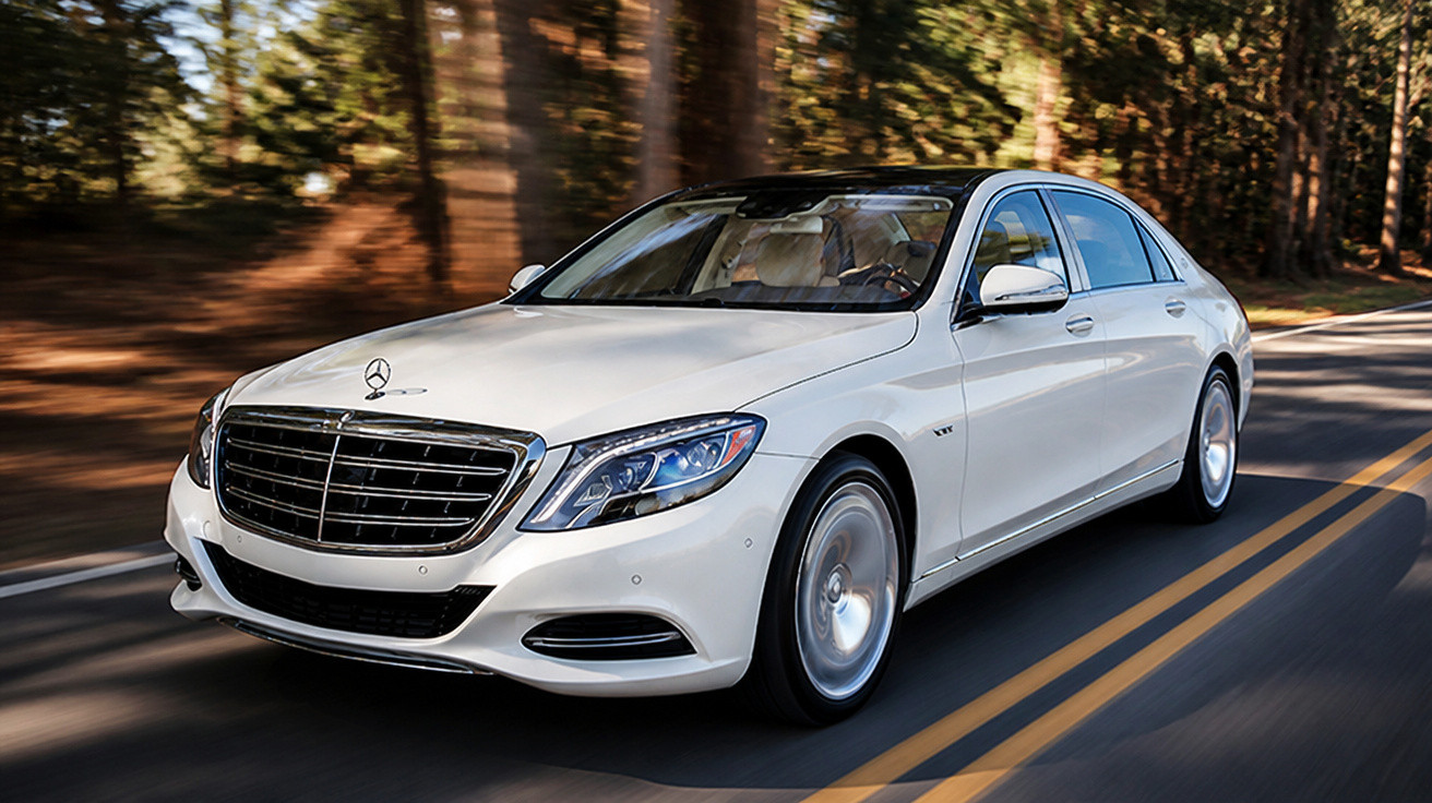 Carro branco de luxo Mercedes-Benz em movimento numa estrada cercada por árvores.