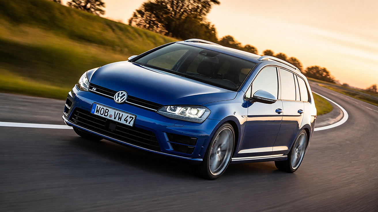 Carro Volkswagen azul em movimento em estrada asfaltada curvada ao entardecer.