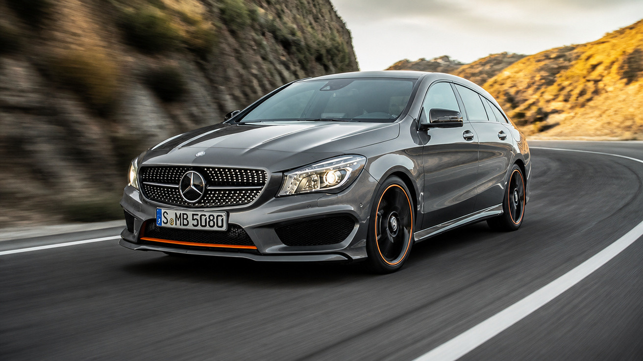 Carro cinza Mercedes-Benz CLA Station em alta velocidade em estrada curvada entre montanhas.
