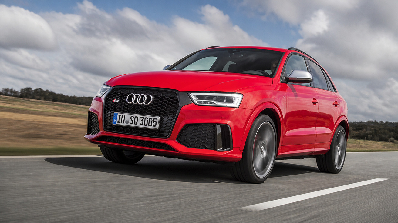 Carro Audi SUV vermelho em movimento em estrada sob céu nublado.