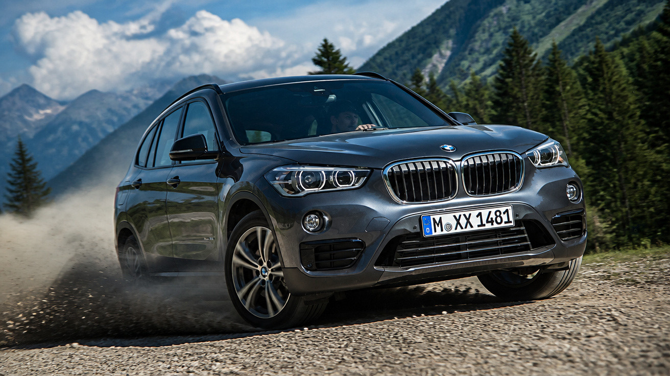 SUV BMW cinza escuro dirigindo em estrada de terra com montanhas e árvores ao fundo.
