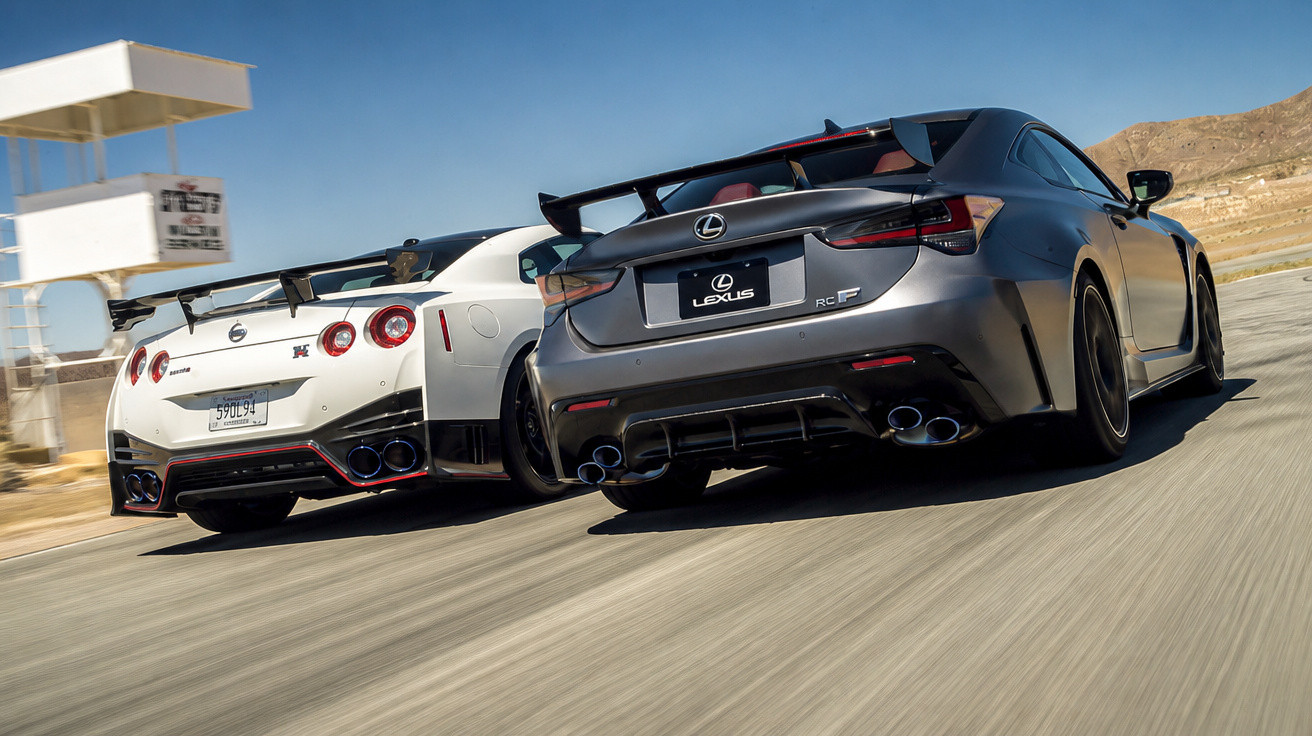 Dois carros esportivos de traseira, um Nissan GT-R branco e um Lexus RC F cinza em pista de corrida.