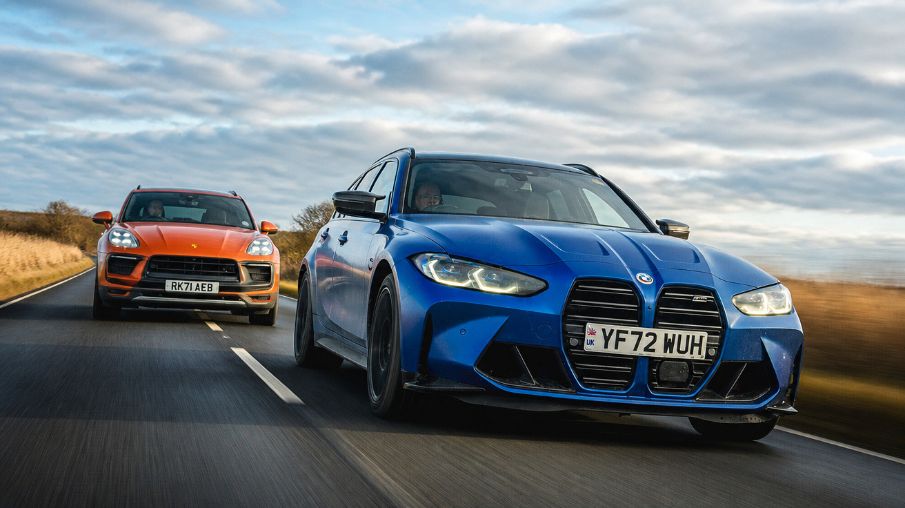 Carros BMW azul e Porsche laranja em estrada reta sob céu nublado em área rural.