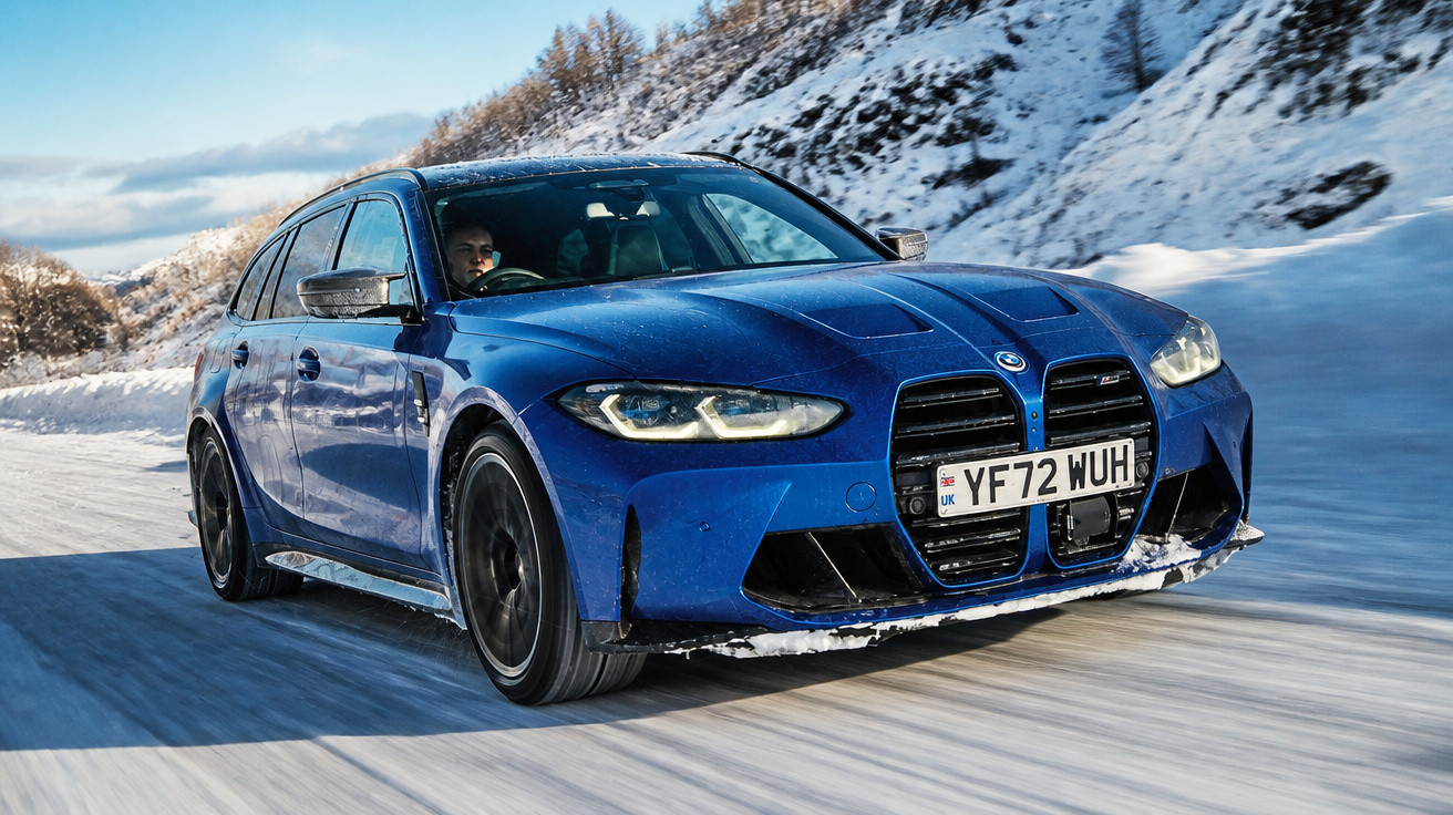 Carro azul BMW em alta velocidade em estrada coberta por neve com montanhas ao fundo.